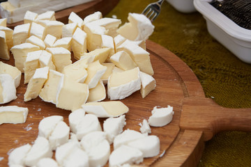 Chef-cook sliced cheese on a cutting board. Cutting ingredients closeup.