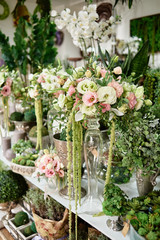 Many flowers on table in florist shop, copy space. Small business. Floral design studio, luxury wedding decorations and arrangements. Flowers delivery. Holiday and floristry concept
