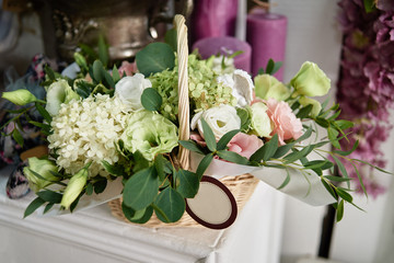Flowers arrangement ib basket on table in florist shop, copy space. Small business. Floral design studio, luxury wedding decorations. Flowers delivery. Holiday and floristry concept