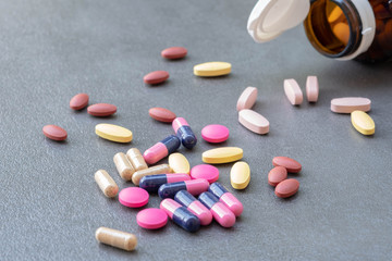 Assorted pharmaceutical medicine and herbal arganic medicine capsules on table dark background.