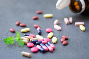 Assorted pharmaceutical medicine and herbal arganic medicine capsules on table dark background.