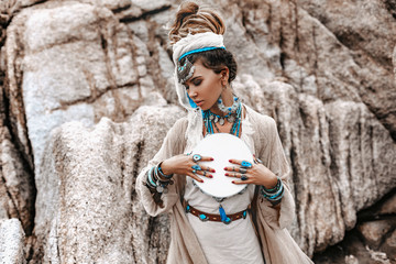 young beautiful woman with lot of boho accessories with the drum outdoors