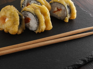 sushi rolls on gray stone slate on wood background