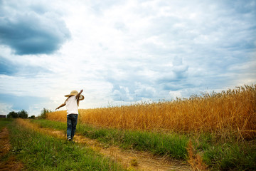 Fototapeta premium Little girl is spinning on a wheat field. Positive emotions and energy. Happy childhood.