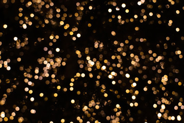 Blurry golden and white fairy chain lights sparkling at night creating beautiful bokeh effect,...