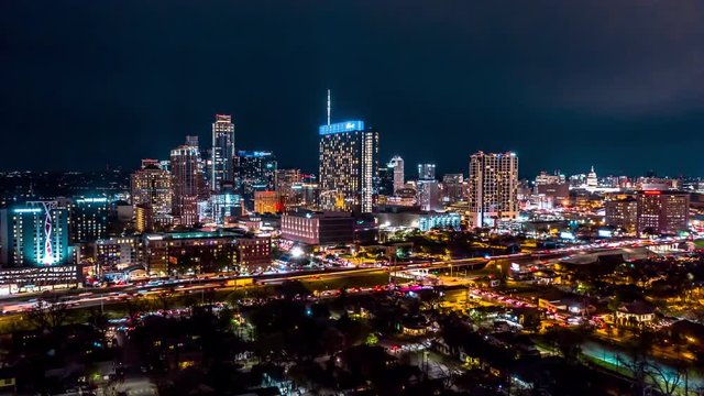 Nighttime hyperlapse of Austin skyline. Drone circles to the right as traffic and skyscrapers light up the city.