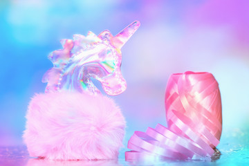 Shiny zine type gradient holographic iridescent head of pink soft fluffy toy unicorn on bright blue pink bokeh fluorescent neon background. Celebration birthday greeting card concept with copy space