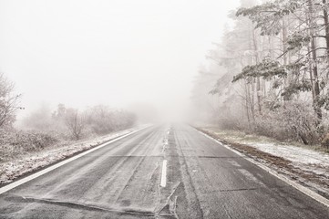 Straight empty wet asphalt road during foggy conditions