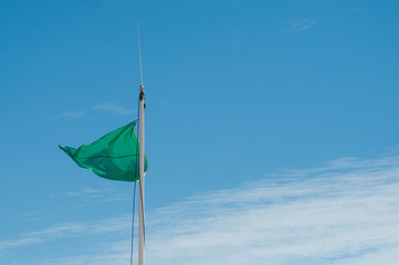 Closeup of green flag on blue sky background