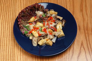 Steamed vegetables with meat on a blue plate on a wooden background