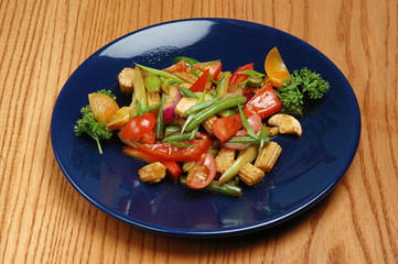 Steamed vegetables on a blue plate on a wooden background