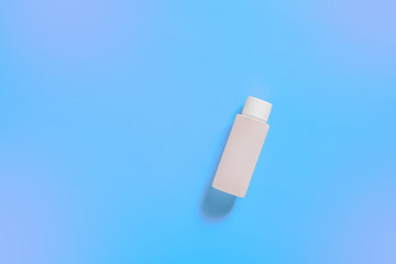White cosmetic bottle on blue neon background, bottle for cosmetic products, purple background