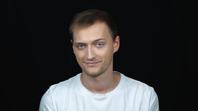 Young caucasian man on black background. Portrait. Emotions and gestures. Close-up. The guy is sexually flirting and looking at the camera.