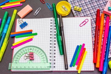Back to school concept. School education supplies on black stone concrete background.