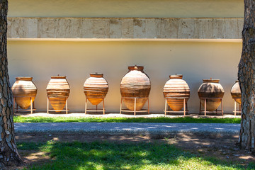 Huge earthenware jugs exhibited in the sun outside. Old pottery pots outside. Old orange clay jugs.