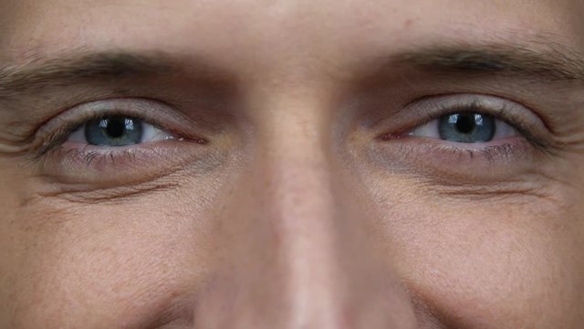 Close up of a male eyes. Detail of opening a blue eyes of a man looking at camera. Happy smiling caucasian male awake looking