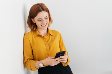 Relaxed young woman leaning against a white wall