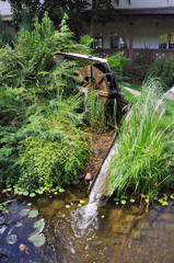 Driving mill wheel with falling water in the garden.