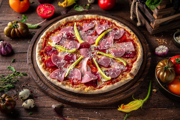 Tasty hot italian pizza with Bacon, Salami, Ham, Cheese Mozzarella, Parmesan, Peppers, Mushrooms, Pepperoni, Tomato Sauce on old wooden table. Pizzeria menu. Concept poster for Restaurants