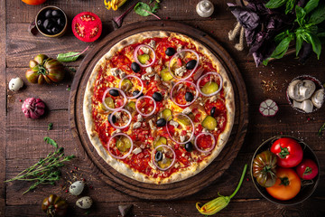 Fototapeta na wymiar Tasty hot italian pizza Mexicana with Pork, Mozzarella, Pepperoni, Pickled Cucumbers, Olives, Tomatoes, Red Onions, Stewed Onions, Tomato Sauce on old wooden table. Pizzeria menu. 