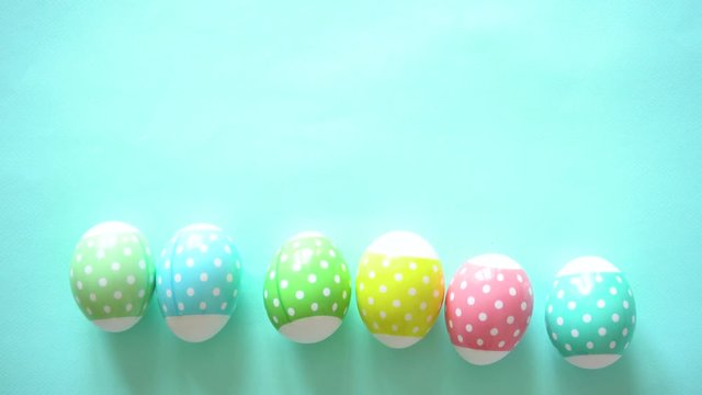 Multi-colored Easter eggs of pastel color with the image of peas, lie exactly along the line and shiver, on a blue background. Copy space