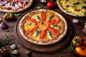 Tasty hot italian pizzas, assorted four cheeses, ham and mushrooms, with salmonon old wooden table. Pizzeria menu. Concept poster for Restaurants or pizzerias