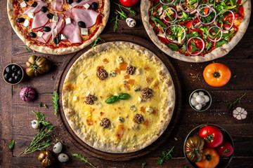 Tasty hot italian pizzas, assorted four cheeses, ham and mushrooms, with salmonon old wooden table. Pizzeria menu. Concept poster for Restaurants or pizzerias