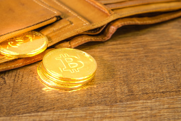 Golden bitcoins Crypto currency in brown leather wallet on wooden table.