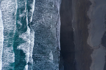 Aerial view of Atlantic ocean waves washing black sandy beach © salajean