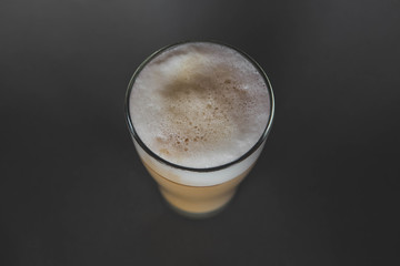 A large transparent glass filled with Latte cooked in a third wave coffee shop is photographed on a gray, isolated background, photo for the menu