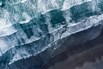 Aerial view of Atlantic ocean waves washing black sandy beach - obrazy, fototapety, plakaty