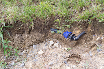 Fototapeta na wymiar Black and blue installation pipe visible in the soil under the green grass surface