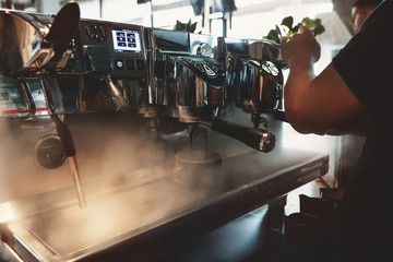 barista man making coffee drink using professional coffee machine steaming around in cafe