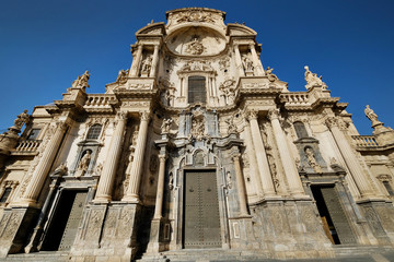 Fototapeta na wymiar Exterior facade of Cathedral Catholic Church of Saint Mary front view against blue sky background, ancient architecture religious monument in Murcia city, Spain