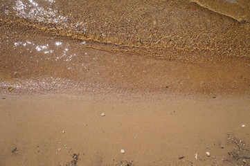 The sun is reflected from the sandy shore of the water.