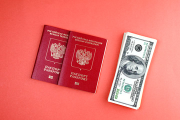 two Russian international passport on orange background lay next to the dollars