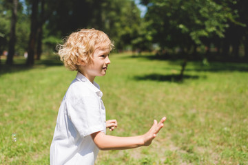 adorable boy in white Gesturing in park with copy space