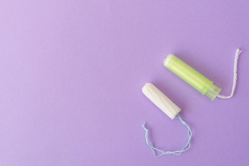 Two cotton tampons with light green applicator and without applicator on a violet background. Hygienic types of tampons. Menstruation, protection, comparison concept, flat lay, Copy space, top view