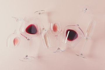 Assorted wineglasses with red, rose and white wine lying on pink background. Wine degustation concept. Flat lay. Top view. Copy space. Toned
