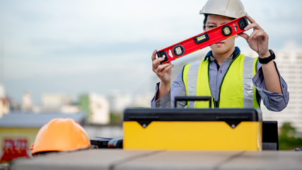 Asian maintenance worker man holding red aluminium spirit level tool or bubble levels over tool box at construction site. Equipment for civil engineering project