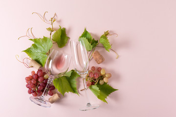 Assorted wineglasses with rose and white wine, grape, leaves and cork lying on pink background. Wine degustation concept. Flat lay. Top view. Copy space