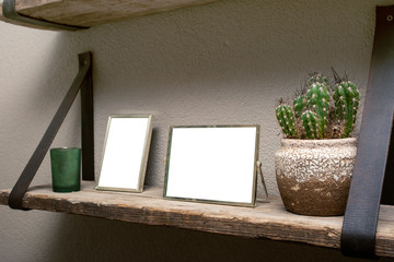 Two blank picture frames and cactus decoration on wooden shelf, industrial retro interior design