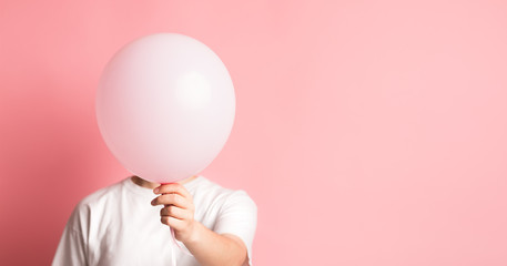 Woman hiding her face beside pink balloon with blank space
