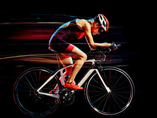 Fototapeta na wymiar one caucasian woman triathlon triathlete cyclist cycling studio shot isolated on black background with light painting effect