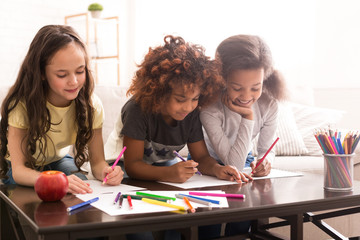 Schoolgirls drawing with colorful pencils at home