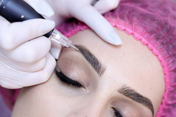 Young woman having permanent makeup on eyebrows in beautician salon	 - obrazy, fototapety, plakaty