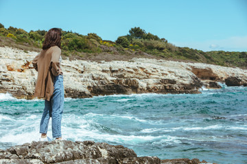 woman standing on cliff enjoying view of the sea. windy weather. sunny day