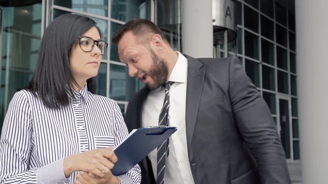 Business man leaving the office touching colleague woman. She slapping him by the face. Sexual harassment.