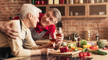 Senior couple in love relaxing with wine at kitchen