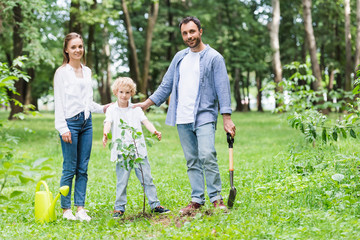 family looking at camera during planting seedlings in park